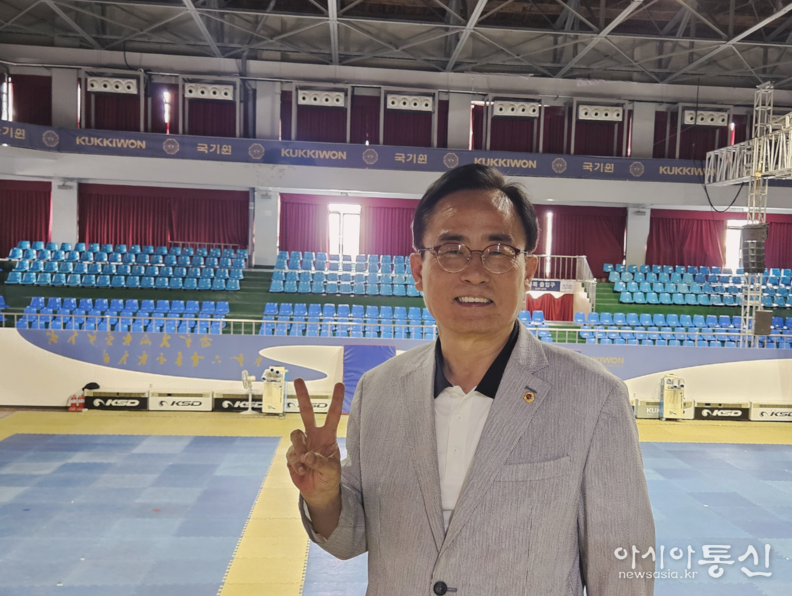 김형재 시의원이 국기원 중앙수련장에 설치 완료된 냉방기 (3층 벽면 위)를 배경으로 기념촬영을 하고 있다.